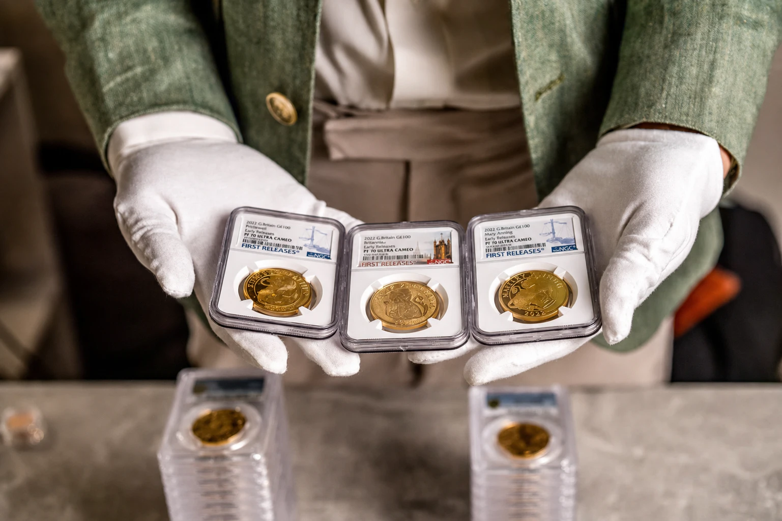 Graded British gold coins presented in white gloved hands