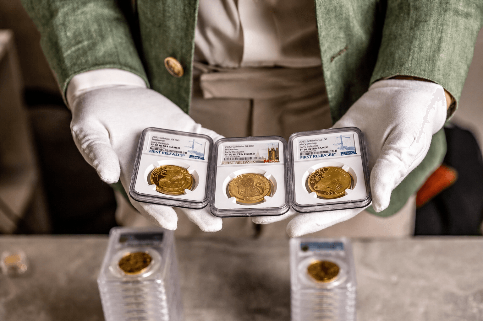 Graded British gold coins presented in white gloved hands