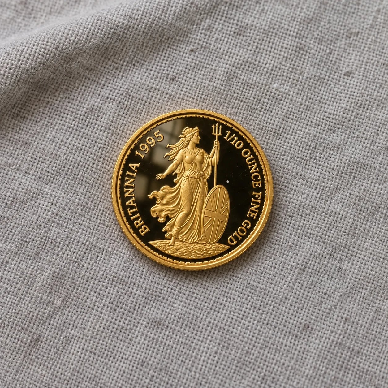 A complete 1995 one-tenth-ounce Gold Britannia proof coin on grey fabric