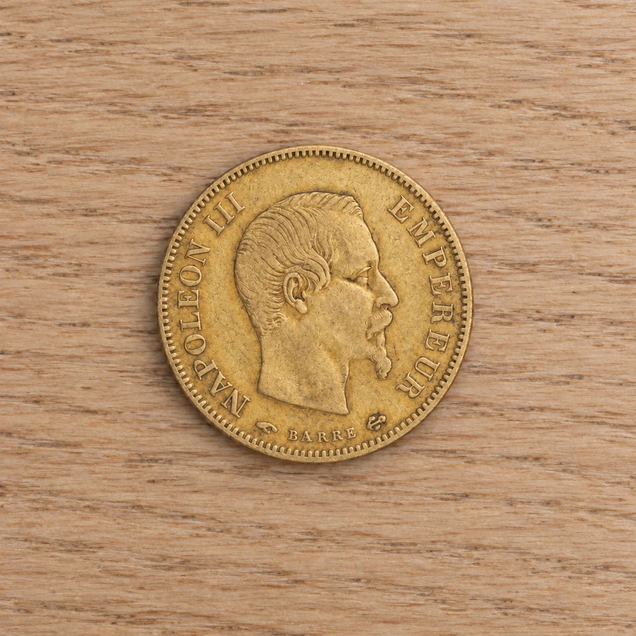A complete handled 1857 French 10 Franc Napoleon III gold coin
