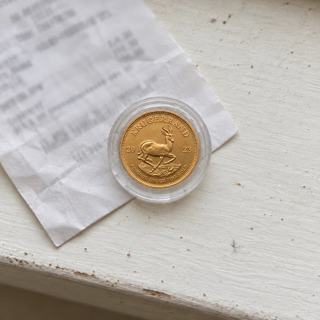 A small complete 2023 one-tenth-ounce Gold Krugerrand coin in a clear capsule