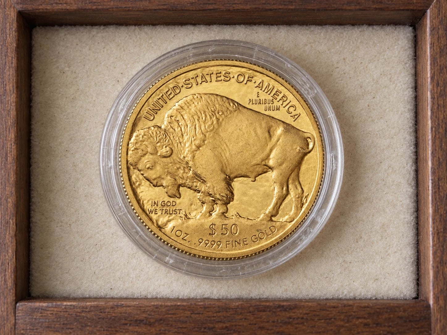 A complete older American Gold Buffalo coin showing the bison reverse in a clear capsule in a tidy drawer