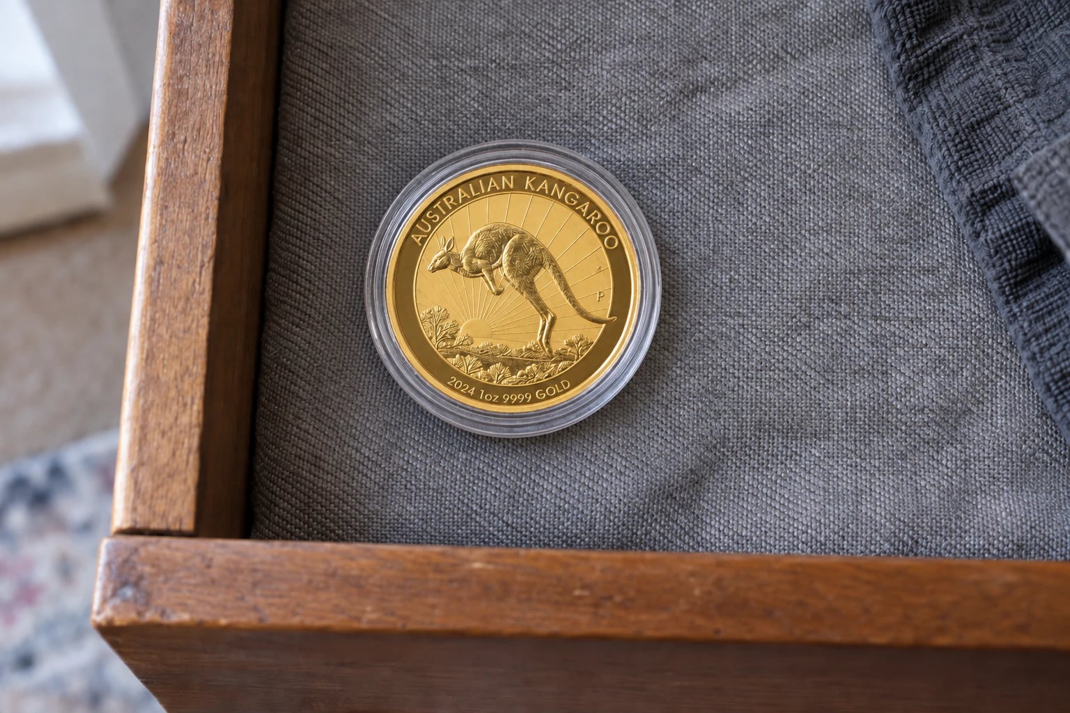 A complete one-ounce Australian Gold Kangaroo coin in a capsule inside a tidy home drawer