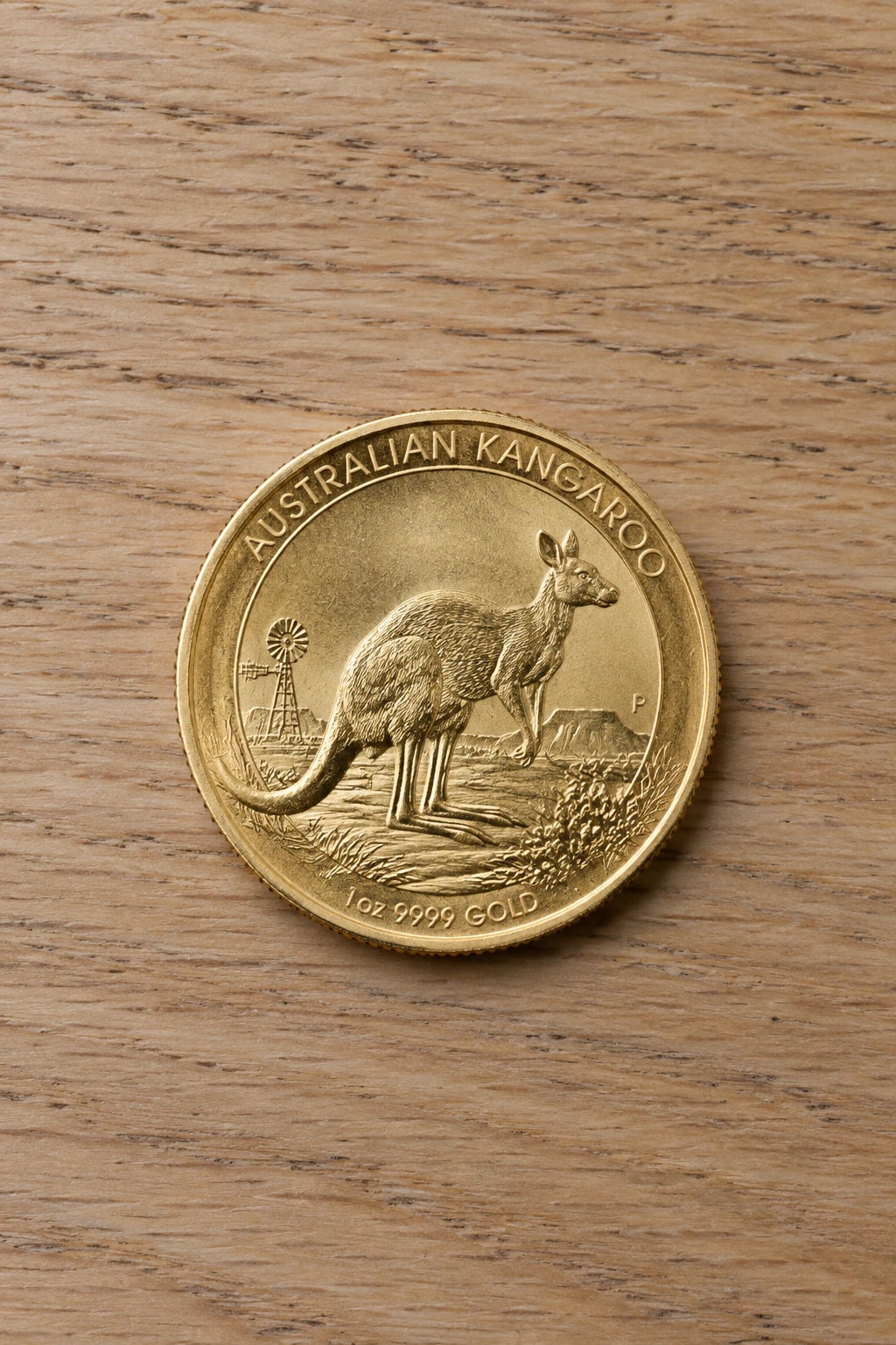 A complete handled one-ounce Australian Gold Kangaroo coin on a clean pale oak table