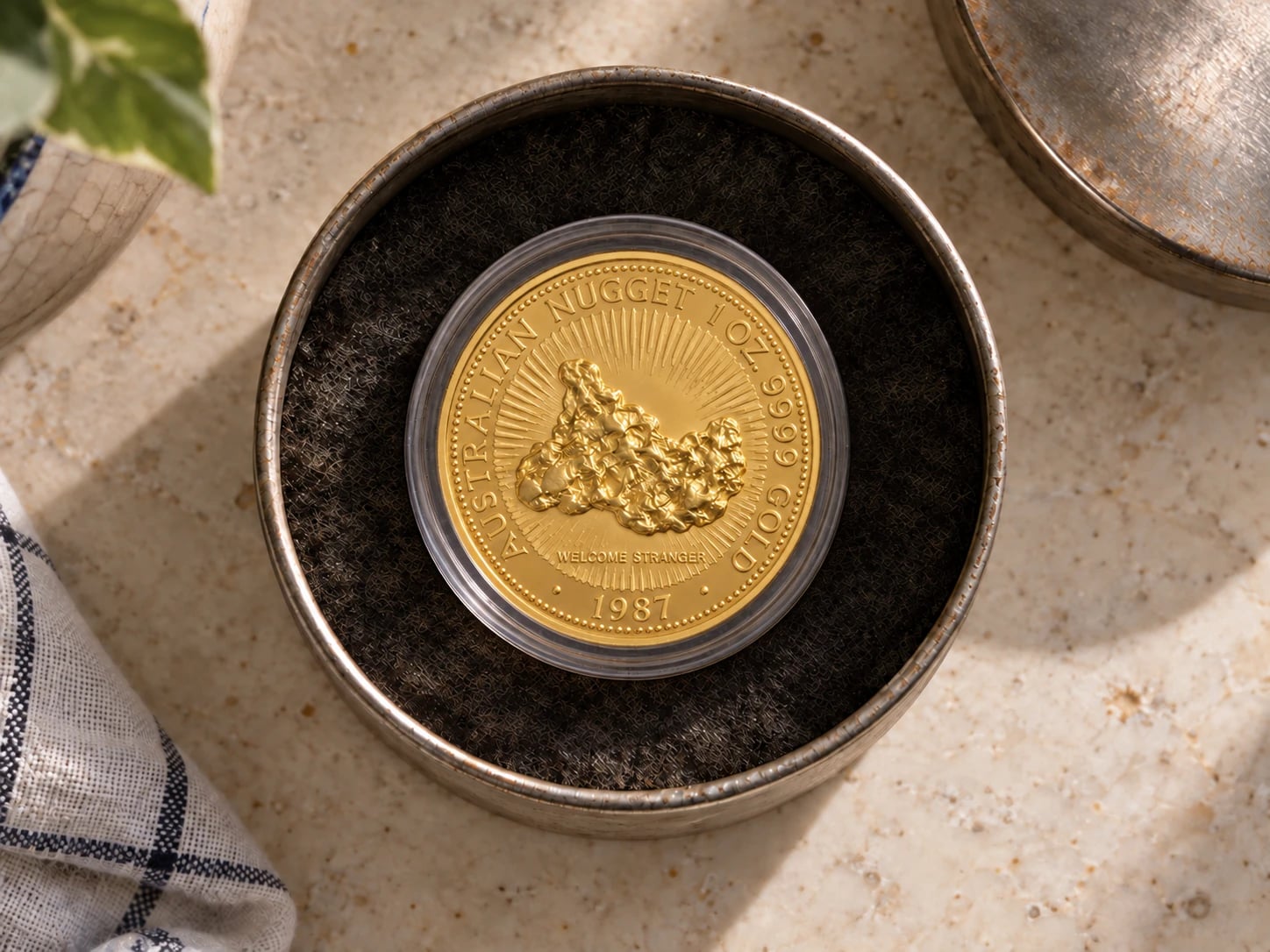 A complete older Australian Gold Nugget coin in a capsule inside a simple keepsake tin