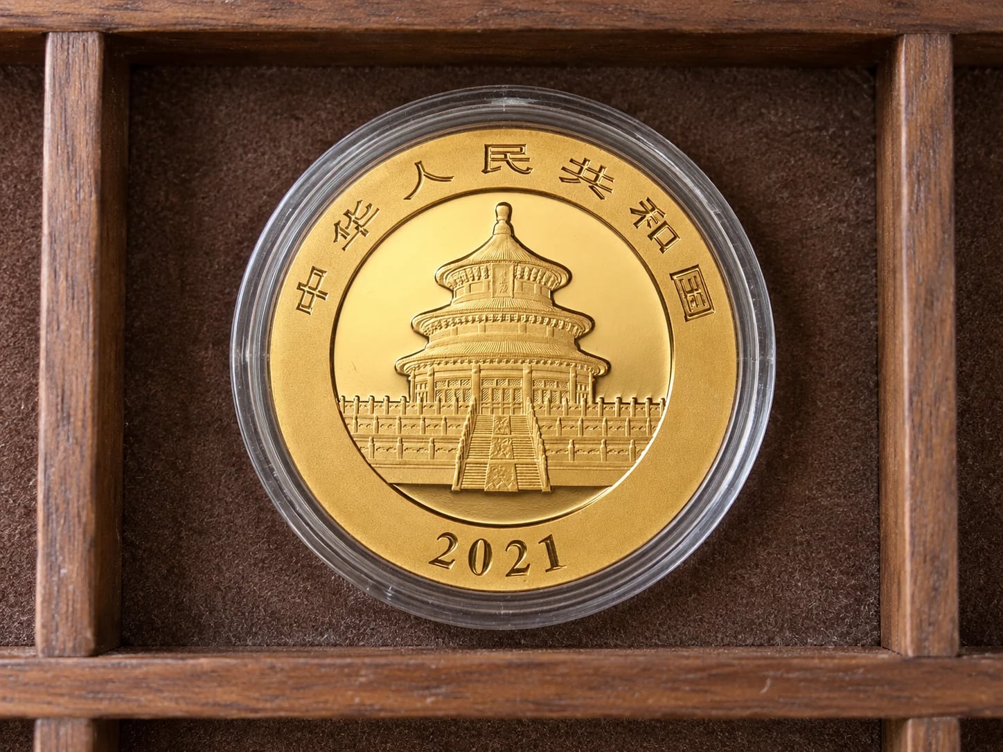 A complete 30g Chinese Gold Panda coin showing the Temple of Heaven in a capsule inside a walnut drawer