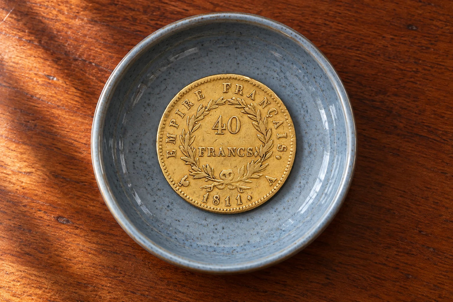 A complete French 40 Franc Napoleon I gold coin kept in a ceramic dish at home