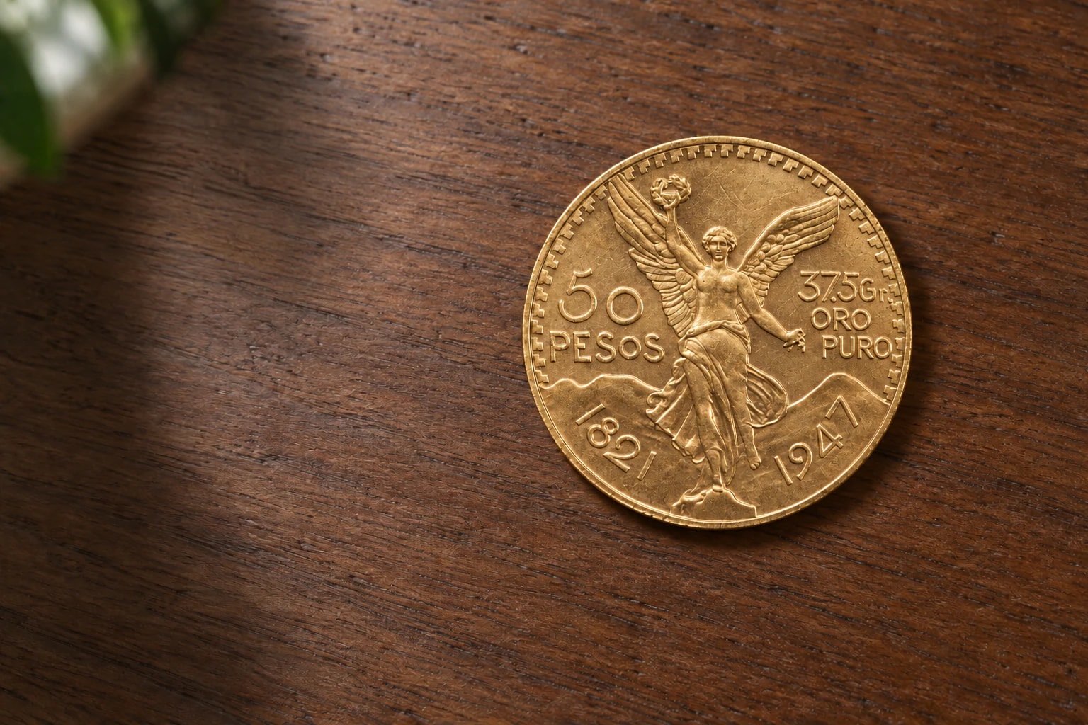 A complete handled Mexican 50 Pesos Centenario gold coin on a clean walnut table