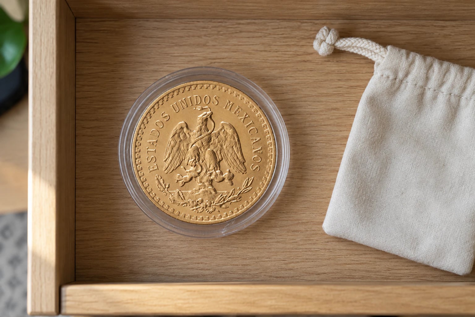 A complete Mexican 50 Pesos Centenario gold coin in a capsule inside a tidy home drawer