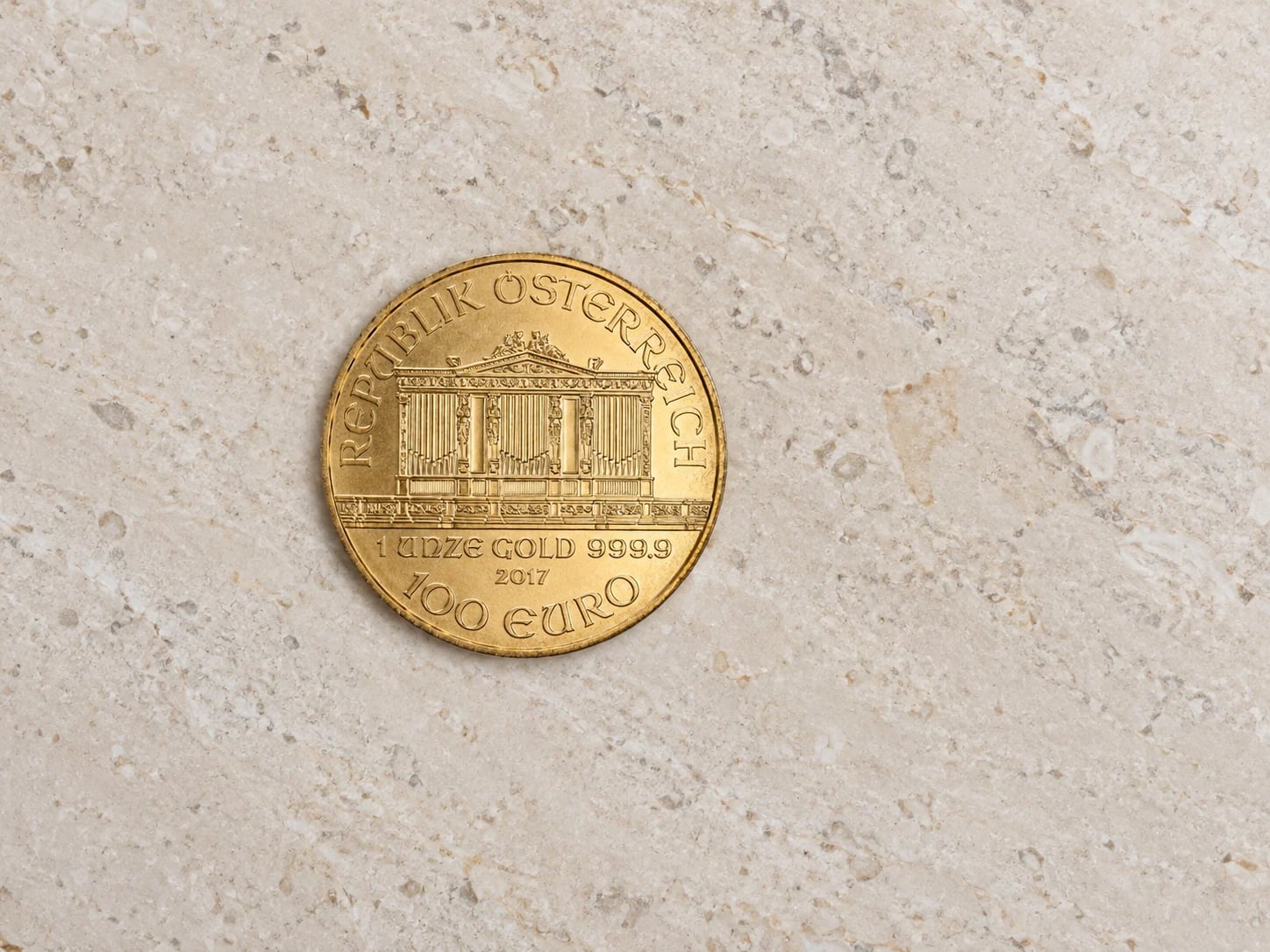 A complete euro-denominated Austrian Gold Philharmonic coin on a clean stone table