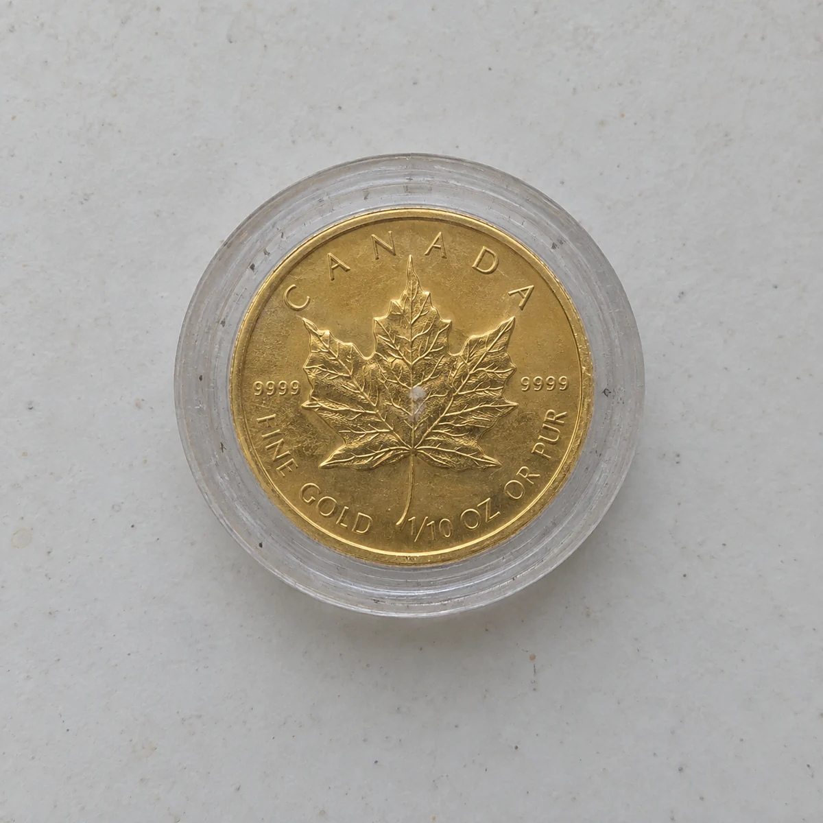 A complete marked one-tenth-ounce Canadian Gold Maple Leaf coin in a cloudy capsule