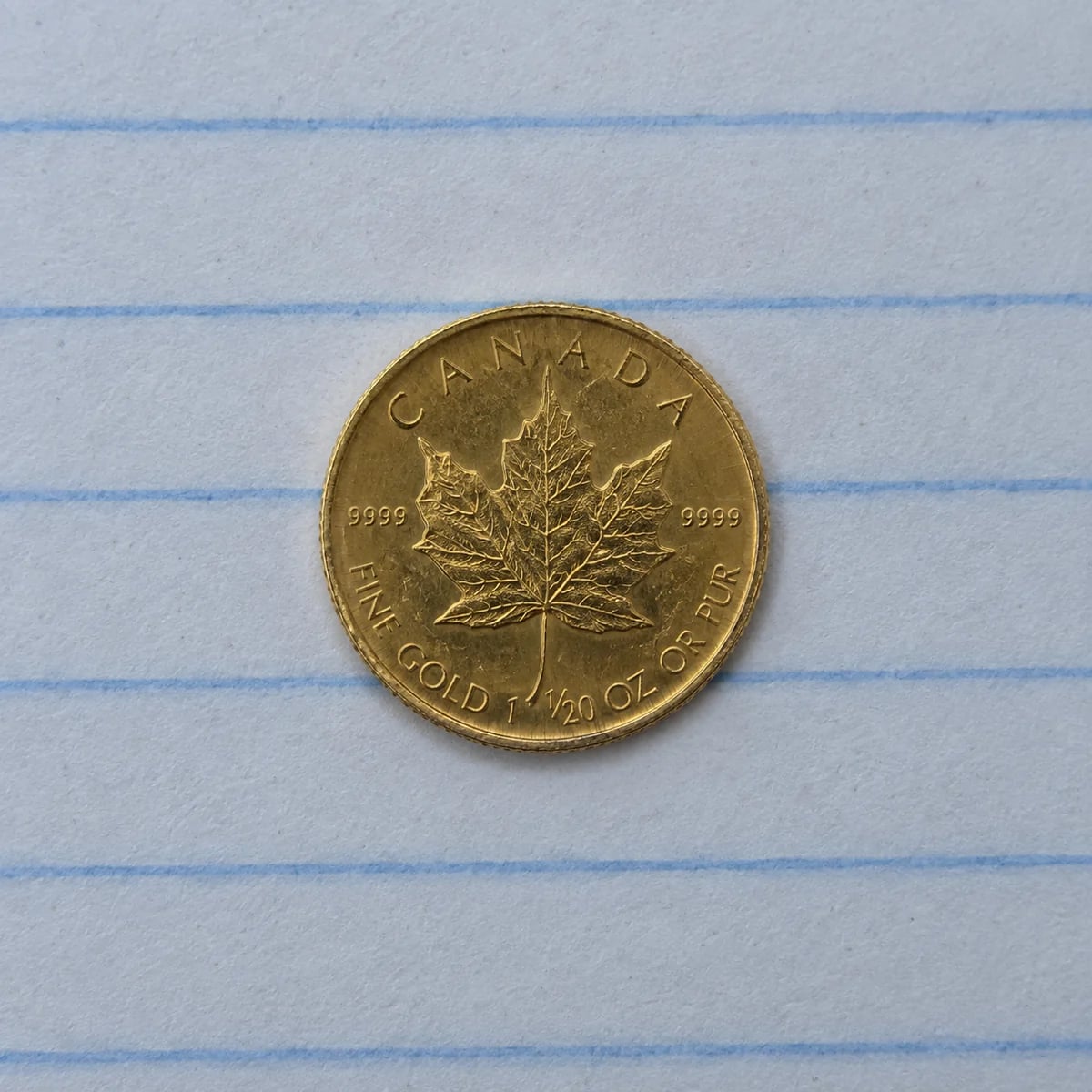 A complete worn one-twentieth-ounce Canadian Gold Maple Leaf coin on notebook paper