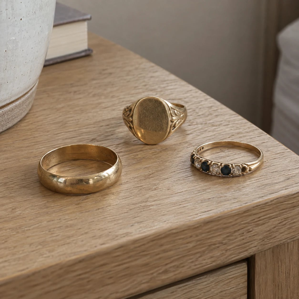 Three different worn gold rings on a pale oak bedside table