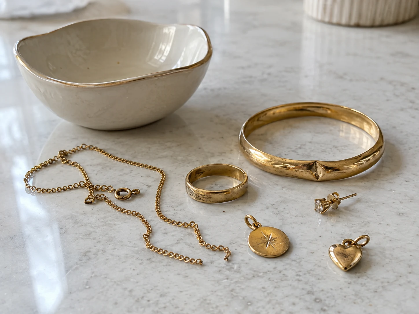 Broken and unwanted gold jewellery beside a ceramic trinket bowl